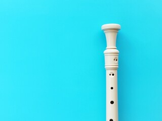 A white plastic recorder is on a blue background and copy space to add text  © MissPic