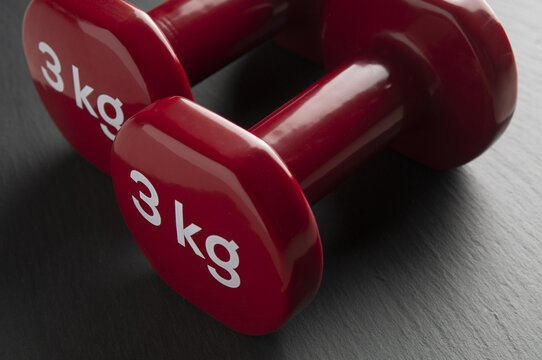 Two red dumbbells close up on a black background
