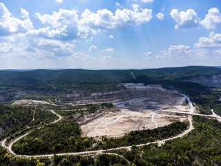 Aerial view of an open limestone quarry among forested hills.