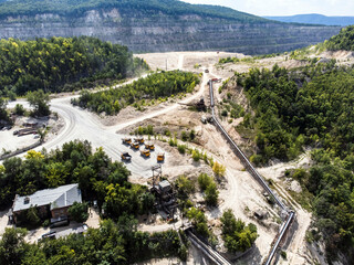 Aerial view of mining trucks queuing to be unloaded onto a conveyor system.