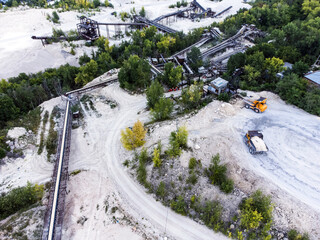 Aerial view of dump trucks unload onto a conveyor system.