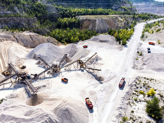 Aerial view of open cast limestone quarry with conveyor system and dump trucks.