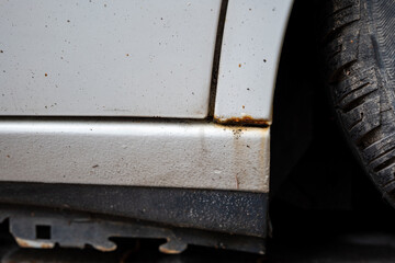 Rusted or rusting door sill of white-painted modern car. Close up shot, no people, bubbling paint