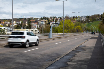 Road traffic speed trap camera in a gray box between 4 lanes of road in a major European city. Blurred traffic, slow shutter speed, no people