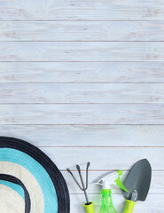 Shovel, rake and spray gun for gardening on a wooden background. Gardening tools and a hat on a...