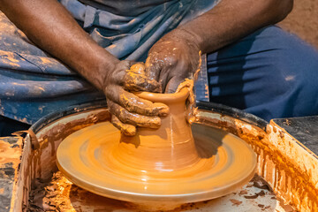 Gros plan sur les mains d'un homme qui fabrique une poterie en argile.	