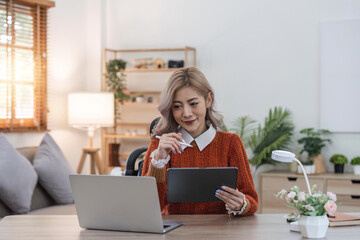 Woman using laptop and tablet on desk of her at home