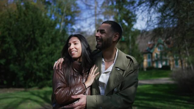 Romantic couple enjoying laughter and love in a peaceful park setting: Authentic moment of happiness shared by happy boyfriend and girlfriend while strolling and embracing outdoors