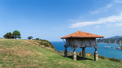 Fototapeta na wymiar Paisaje típico de la costa asturiana, con un verde prado y hórreo en Cadavedo, España.