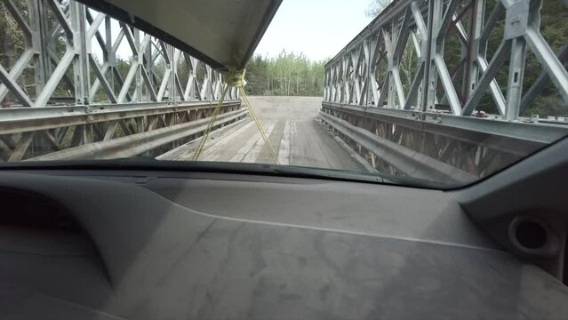 Car driving through a brodge in a forest in Northern Ontario and carrying a canoe