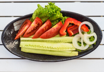 Fresh vegetables cucumber and tomatoes in plate on wooden table