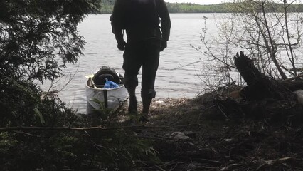 Caucasian men pulling the canoe out of the waters of Lake Whiskey in Northern Ontario Canada
