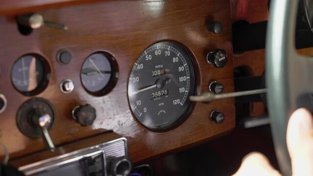 Retro old vintage red car driving in a city road in sunny summer day. Inside cabin - driver, steering wheel and dashboard.