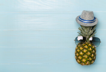 Creative pineapple hipster in sunglasses on wooden background, top view