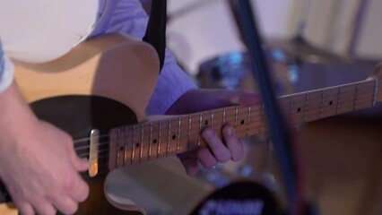 The guitarist plays the guitar. A musician in a musical group on stage gives a concert. Stage light