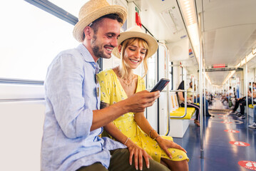 Couple travelling in the subway and looking at cell phone