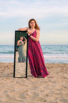 Woman in long dress with mirror on beach