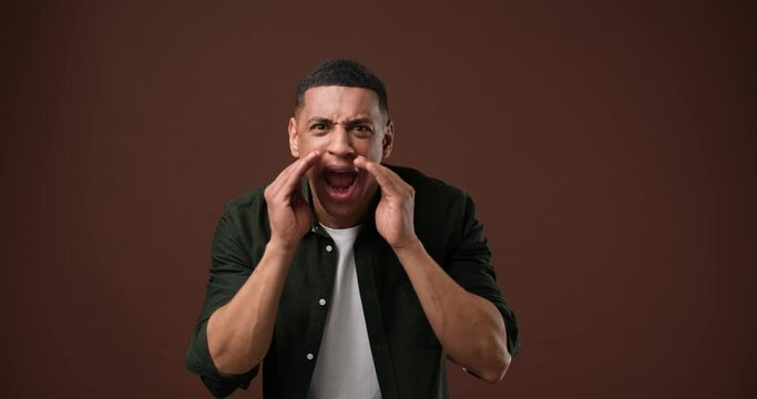 Closeup serious angry african american guy shouting standing over on brown studio background