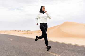 Beautiful middle-eastern arab woman wearing hijab training outdoors in a desert area - Sportive athletic muslim adult female wearing burkini sportswear doing fitness workout