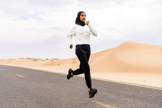 Beautiful middle-eastern arab woman wearing hijab training outdoors in a desert area - Sportive athletic muslim adult female wearing burkini sportswear doing fitness workout - Powered by Adobe