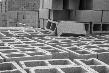 Many hollow concrete blocks for construction of masonry walls of a single-family suburban house on site in west central Florida, in black and white. Selective focus.