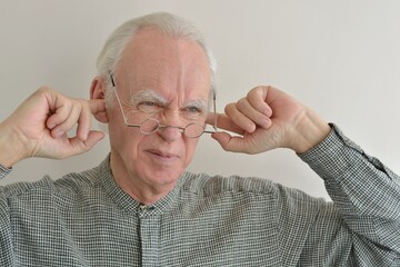 Portrait of an elderly gray-haired man in glasses with an angry, displeased expression on his face...