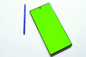 Smartphone mockup with green screen, stylus pen on the side, top view, isolated on white background