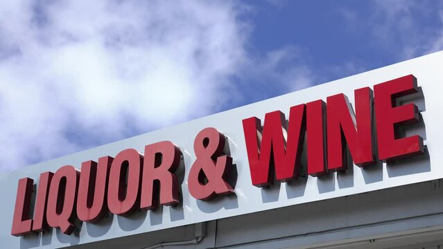 A Sign For A Liquor And Wine Store Against A Bright Blue Sky