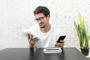 Close up of unhappy man sitting at the table, stressed and confused by calculate expense from...