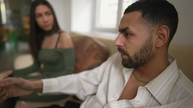 Angry muted boyfriend sitting in silence during argument with girlfriend. Upset young man with serious expression feeling annoyed by girlfriend's nagging