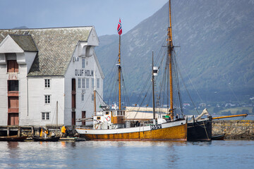Historic sailing boats parking at an old dock in the city of Ålesund in Norway