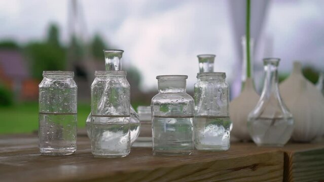 Glass transparent flower vases with water on the table. Preparation for holiday, party, wedding reception.