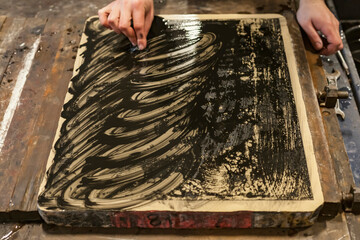 The artist is cleaning a Lithographic limestone with a clotch and chemicals in an art workshop.
