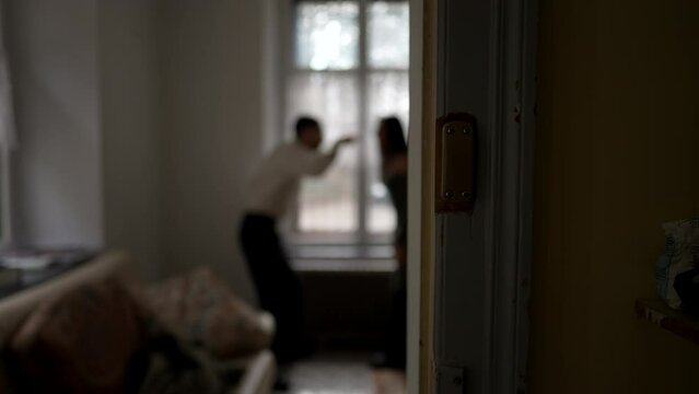 Blurred shot of couple arguing at home. Candid moment of husband and wife fighting each other. Person threatening the other in discussion
