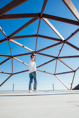 a woman a stands at a large wooden structure walk