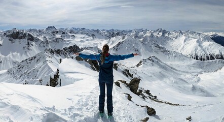 young woman enjoying the view from a high mountain peak Alplihorn above Monstein Sertig Davos. mountaineering in winter