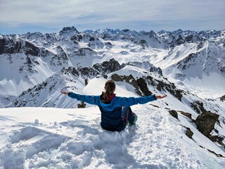 young female skier enjoys the view of the beautiful mountains on a ski tour in the swiss alps. Above Monstein. High quality photo