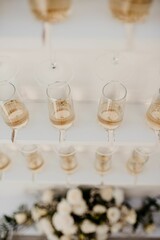 Vertical shot of glasses full of champagne hanging from the wall on the blurred background