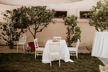 Small table with a white tablecloth and a bouquet-candle decoration prepared for a wedding ceremony