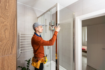 Professional handyman working in shower booth indoors