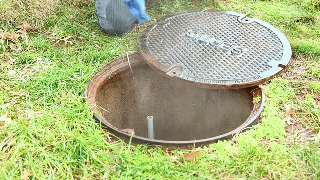 Close up Video of a working plumber opening the lid of a septic system tank,