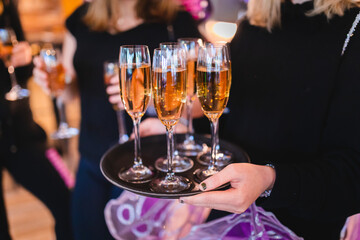Hands holding a brick of  champagne glasses. 