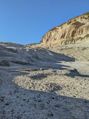 Aerial shot of sandy earth and a rocky hill under the bright blue sky