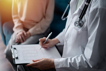 Doctor woman and kid boy patient at home medical exam. The pediatrician filling up medical form on clipboard, close up. Medicine, healthcare concepts
