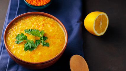 Bowl of lentil soup on a blue linen napkin. Red lentil soup with fresh parsley. Traditional middle eastern food. Close up