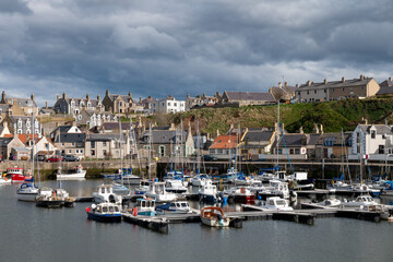 Fototapeta na wymiar 5 April 2023. Findochty Harbour,Moray,Scotland. This is the Harbour and Marina area of the Moray Coast Fishing Harbour with a stormy sky and clouds forming but the sun still shining.