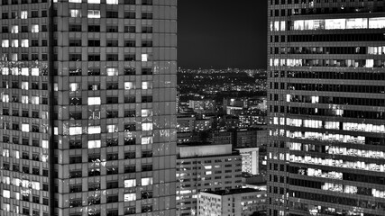 Obraz premium View of at night glass buildings and modern business skyscrapers,. View of modern skyscrapers and business buildings in downtown. Big city at night. Black and white.