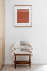 art poster and decorative cushions on wood stand in hallway