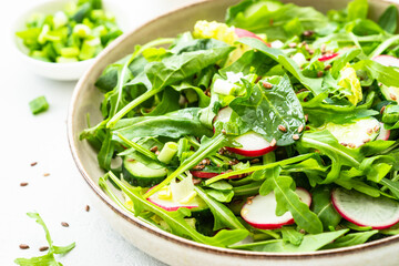 Obraz na płótnie Canvas Spring salad with spinach, arugula, radish with olive oil and seeds.