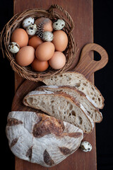 Sliced handmade bread and a basket of chicken and quail eggs.